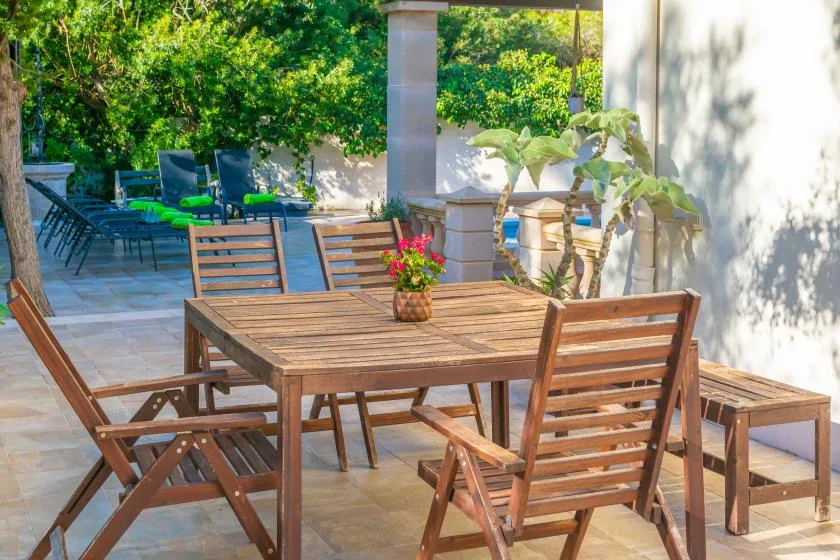 A tiled outdoor patio with a wooden dining table and chairs.