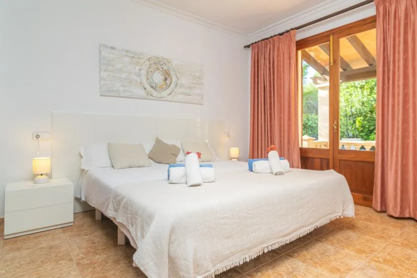 A bright bedroom with a neatly made bed beside a large window.