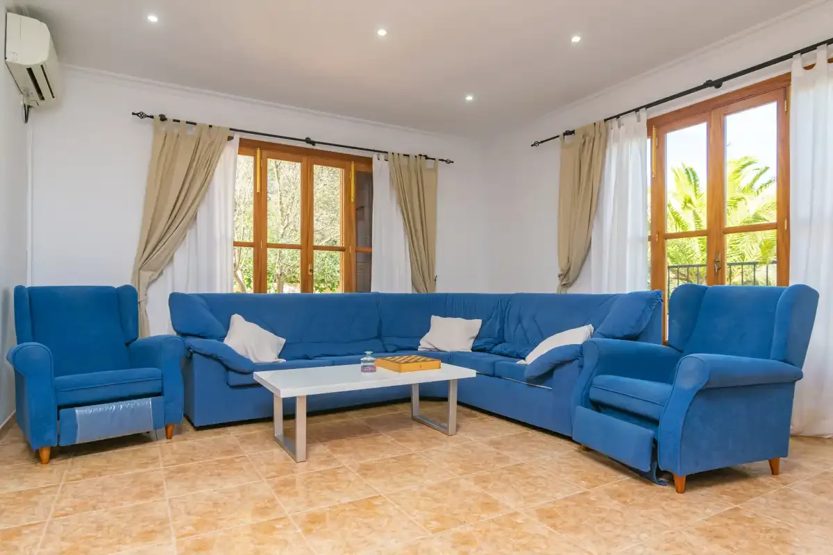 A living room with blue seating, a coffee table, and large windows.