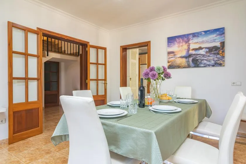 A dining room with a table set for a meal and a colorful seascape on the wall.