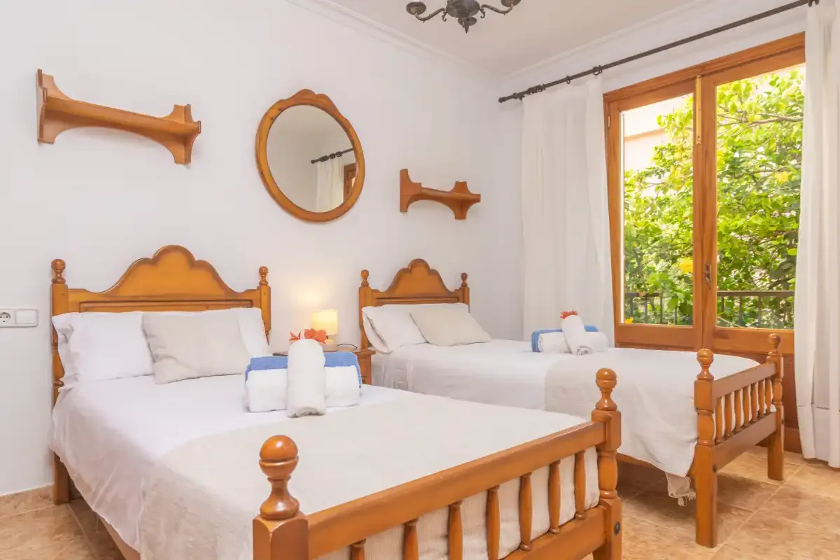 A bedroom with two beds and a large wooden-framed window.