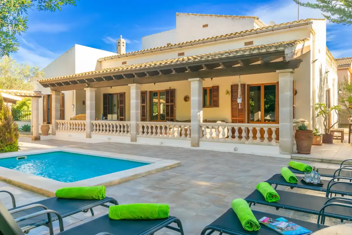 A patio beside a swimming pool, with outdoor seating in front of a house.