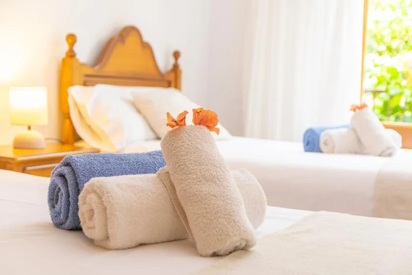 A bedroom with a neatly made bed and folded towels in the foreground.