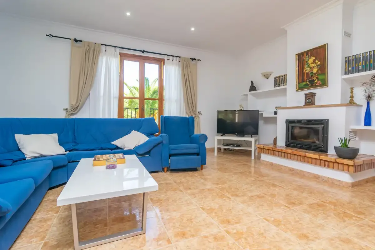 A living room with blue seating, a television, and a fireplace.