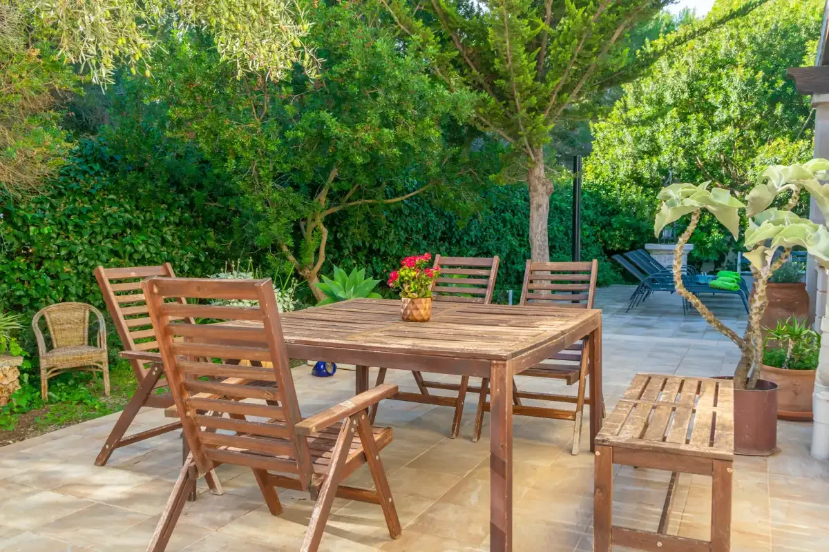 A garden patio with a wooden dining table and surrounding greenery.