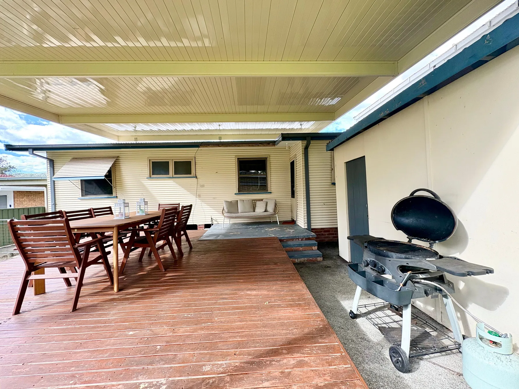 A covered outdoor deck with dining seating and a barbecue.