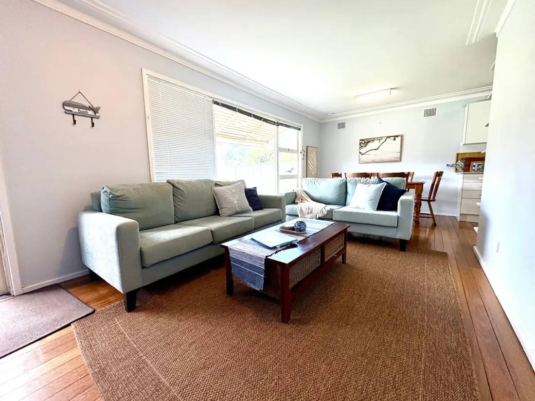 A bright living room with seating around a wooden coffee table and a rug.