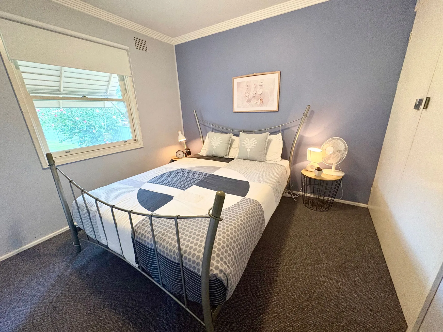 A bedroom with a double bed, bedside tables, and a window.