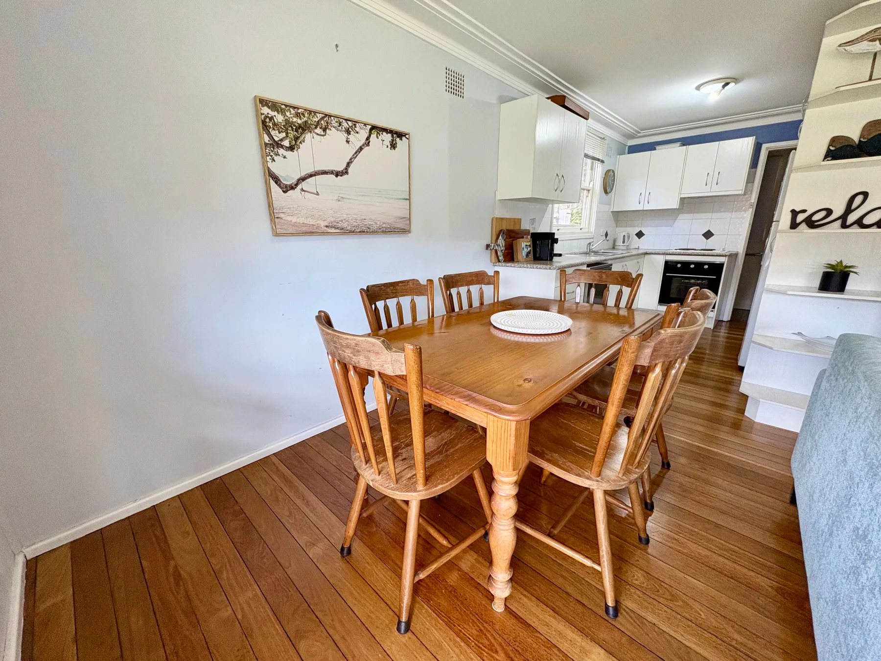 A dining area with a wooden table and chairs beside the kitchen.