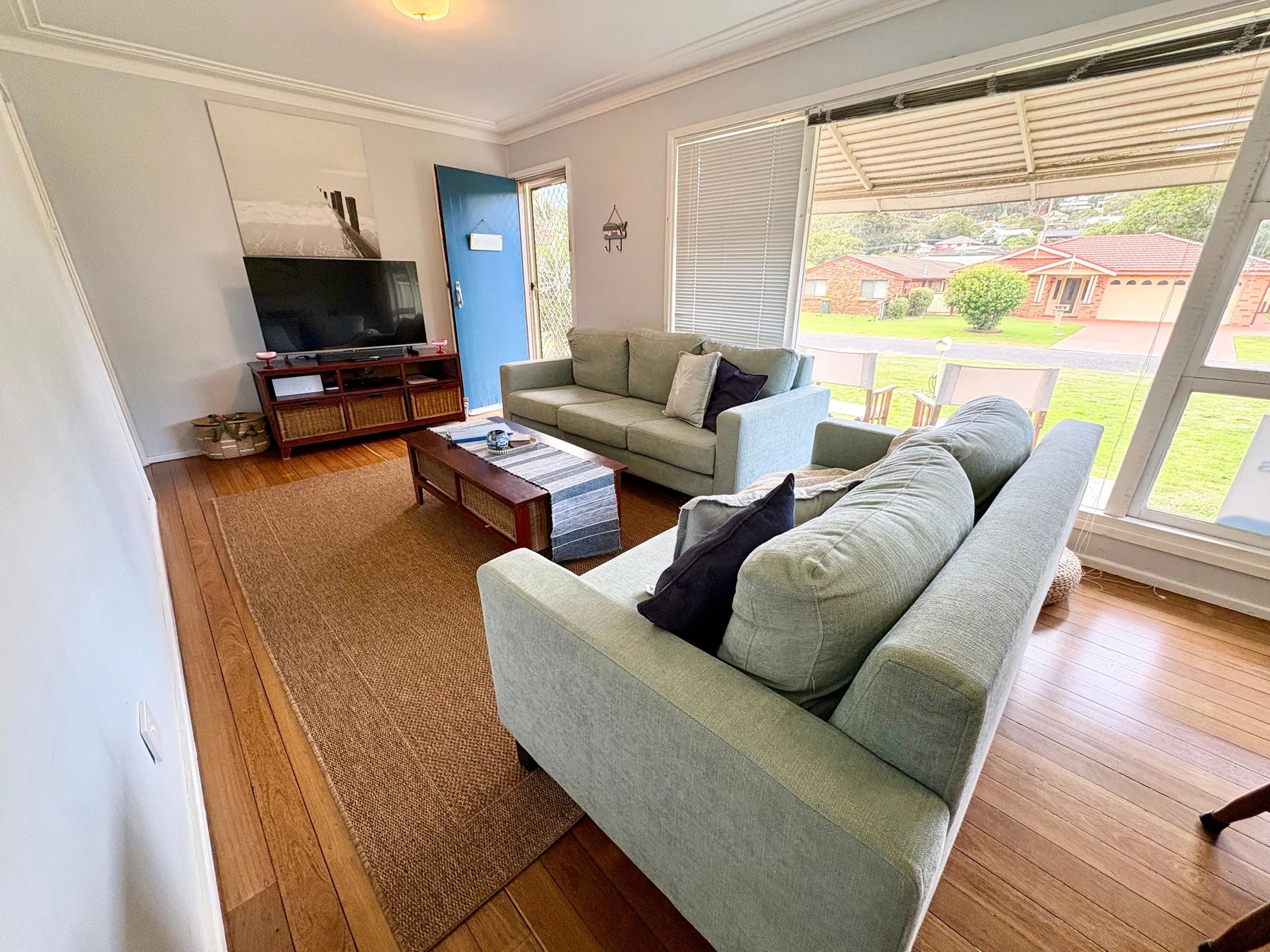 A living room with seating, a television, and large windows overlooking the street.