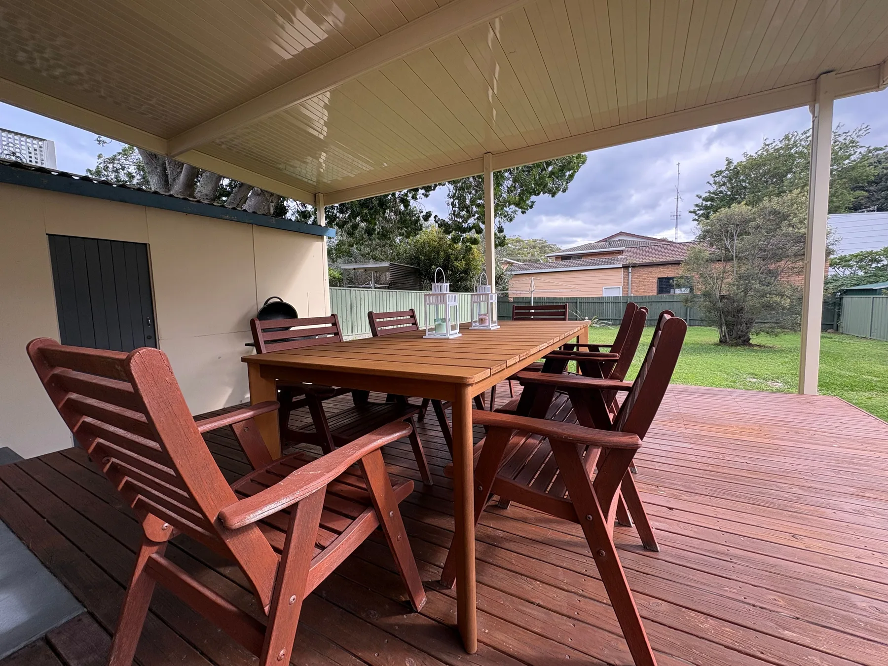 A covered outdoor dining area with a wooden table and seating.