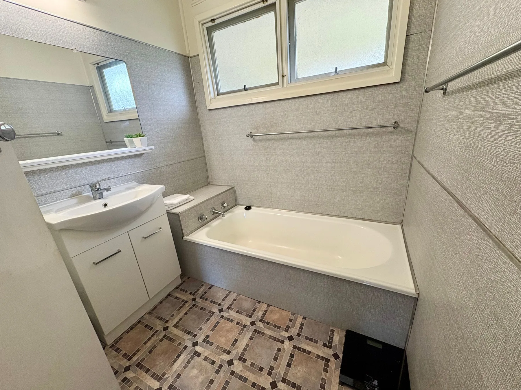 A bathroom with a bathtub, sink, and patterned floor.