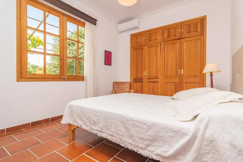 Un dormitorio con una cama, un armario de madera y una ventana grande.