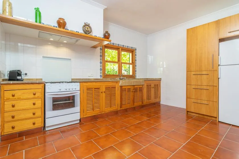 Una cocina con gabinetes de madera, una estufa y una ventana.
