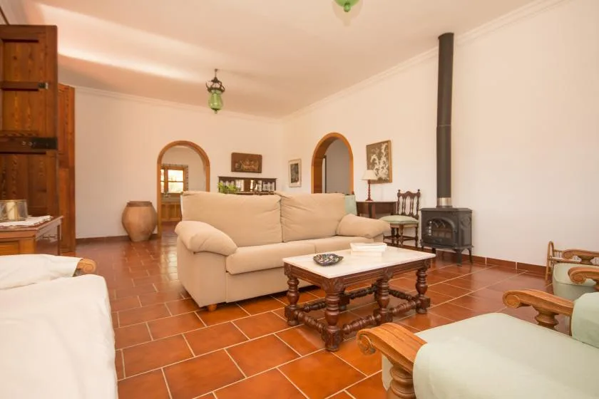 Una sala de estar con asientos beige, una mesa de centro de madera y una estufa independiente.