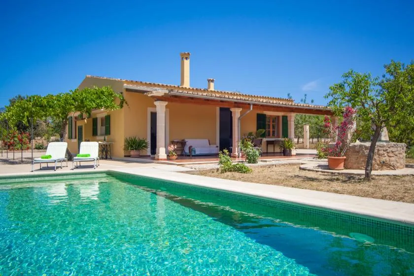 Una casa con patio cubierto da a una piscina y un jardín.