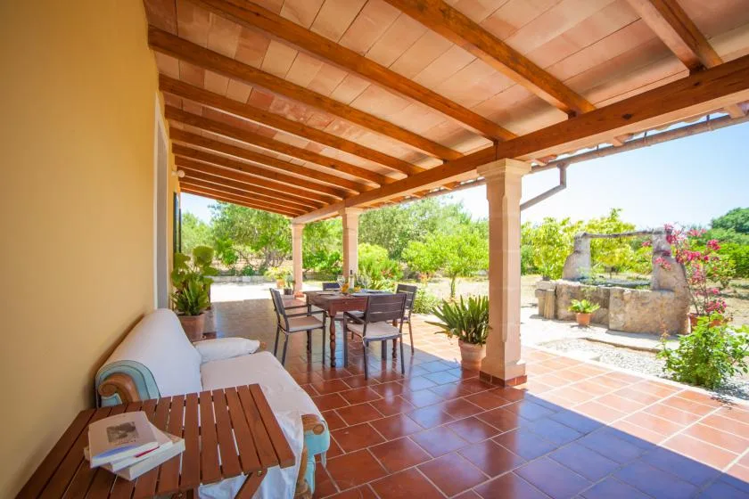 Un patio cubierto con asientos al aire libre da a un jardín.