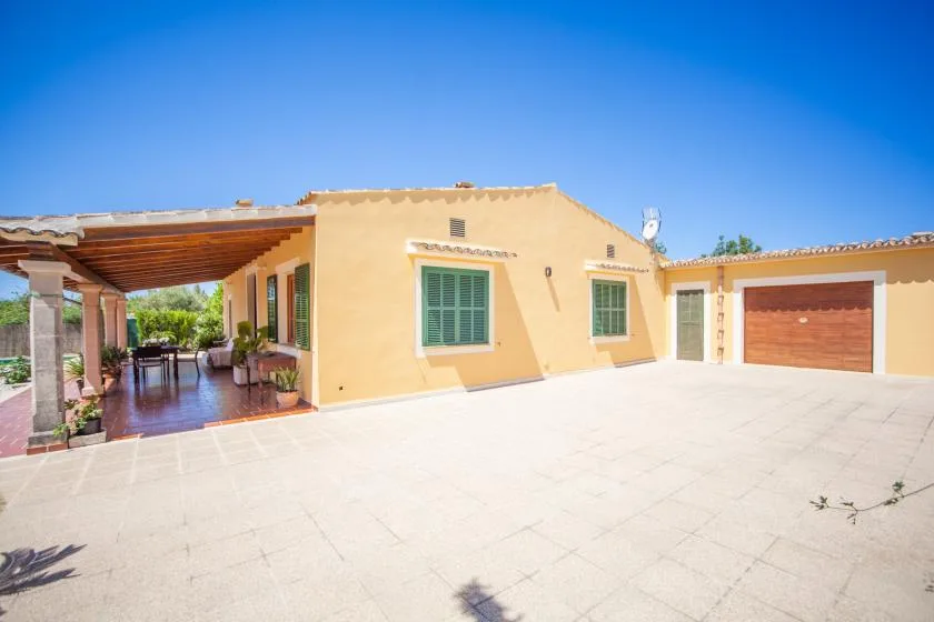 Una casa amarilla con un patio cubierto y un garaje.