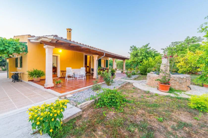 Una casa amarilla da a un patio cubierto con asientos al aire libre y jardín.