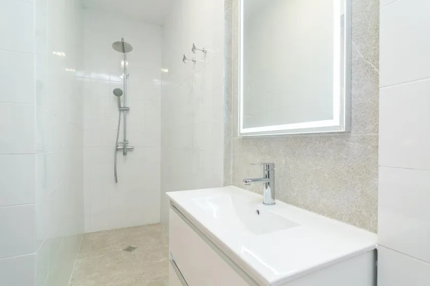 Un baño luminoso con azulejos, ducha y lavabo.