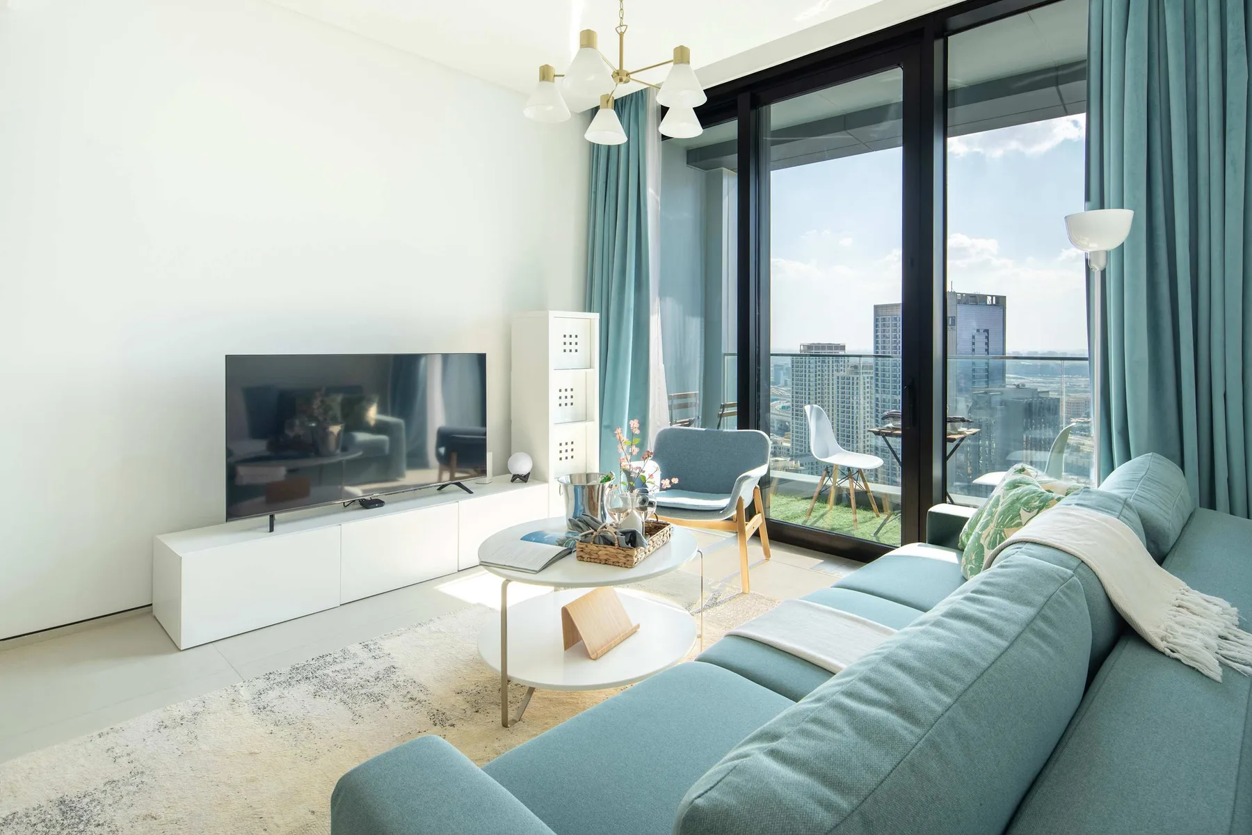 Una sala luminosa con televisor, asientos y grandes ventanales con vistas a la ciudad.