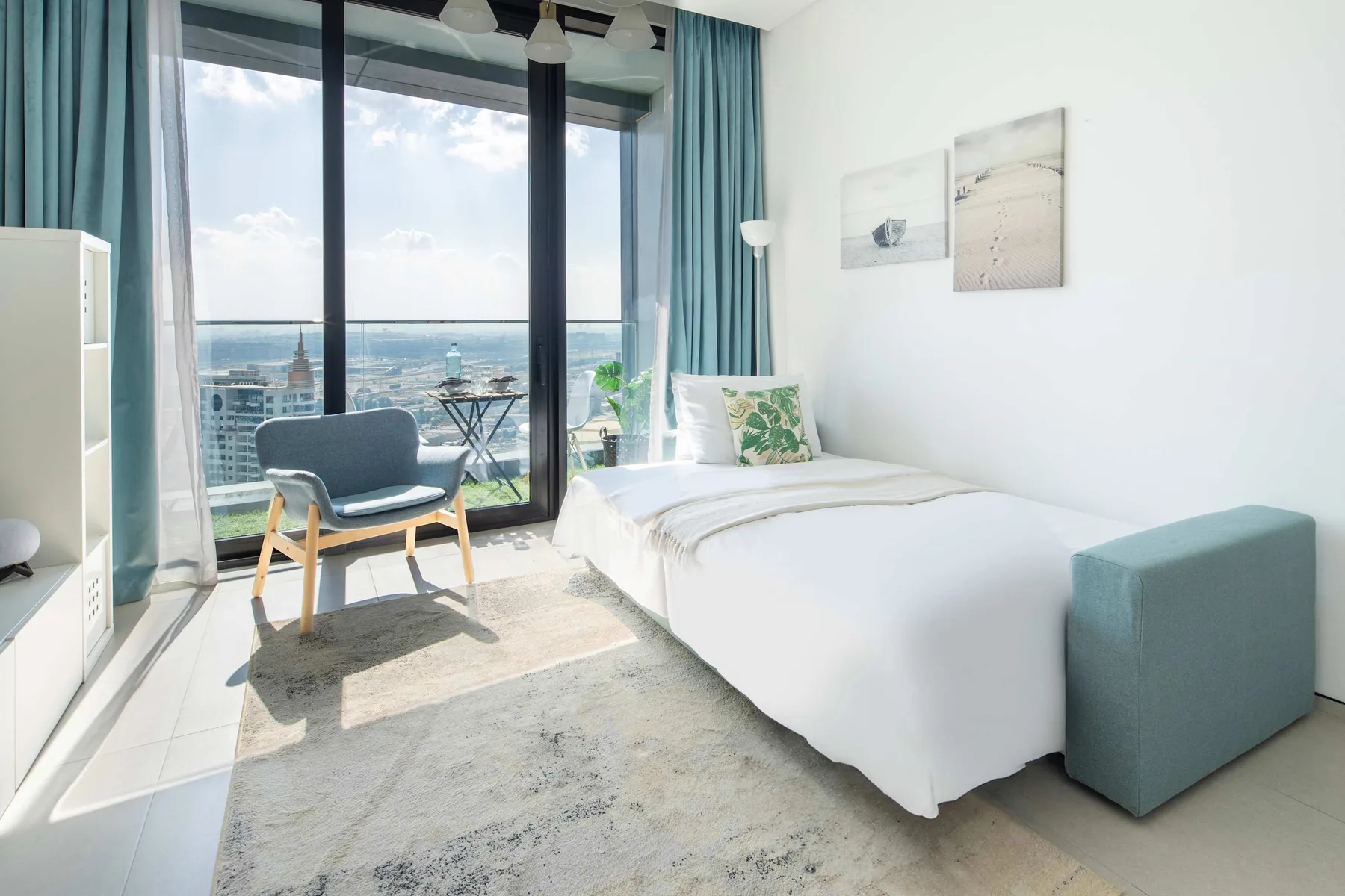 Un dormitorio luminoso con una cama junto a grandes ventanales con vistas al agua.