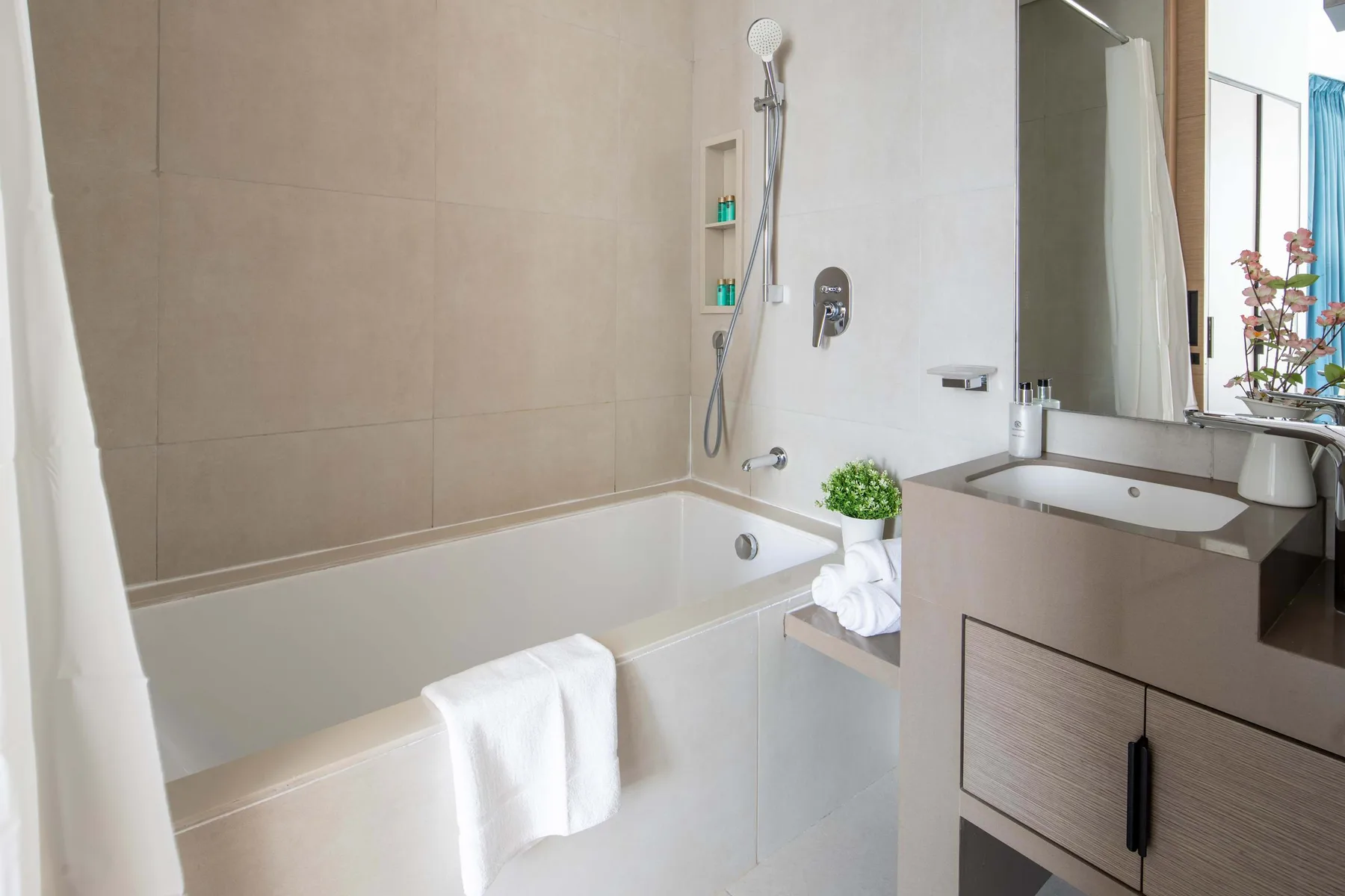 Un baño con bañera, ducha de pared y lavabo con mueble.