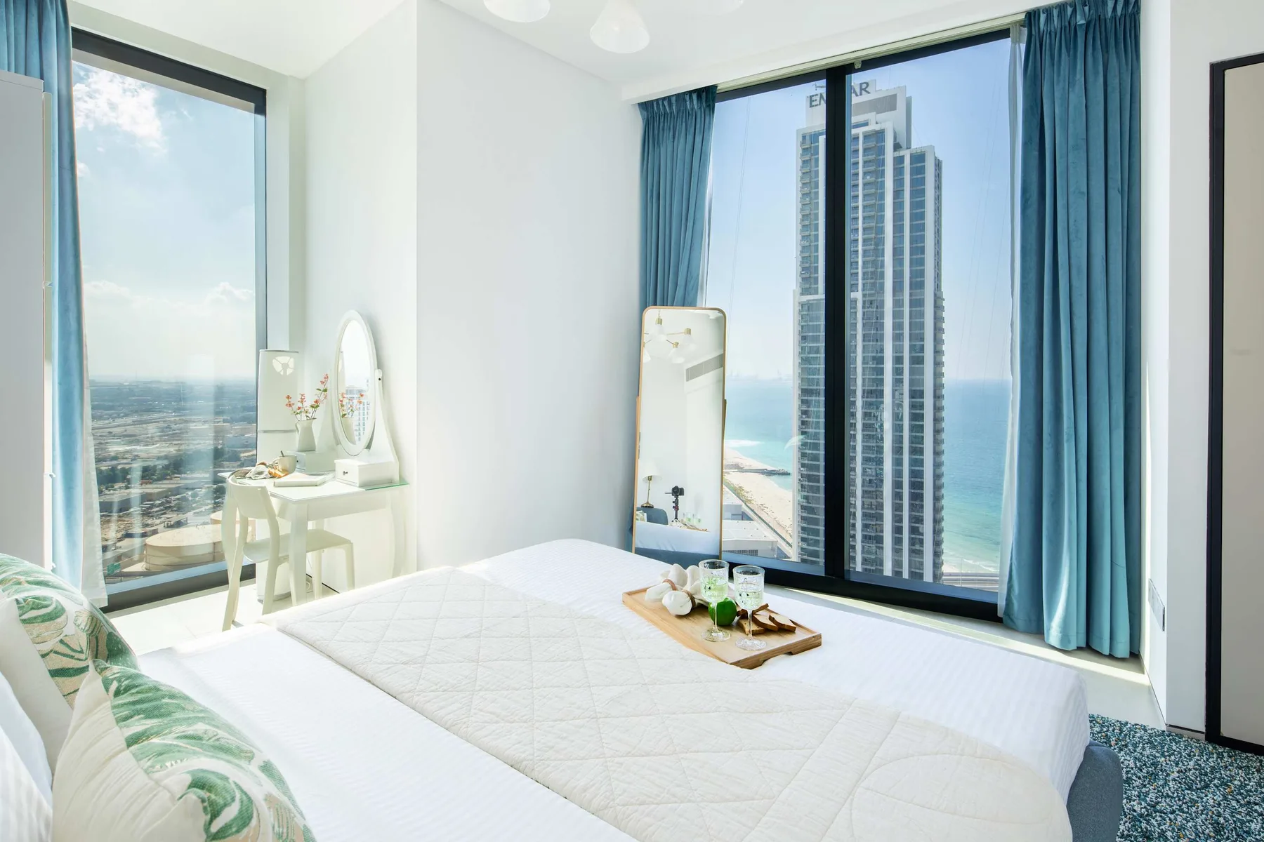 Un dormitorio luminoso con una cama junto a grandes ventanales con vistas al mar.