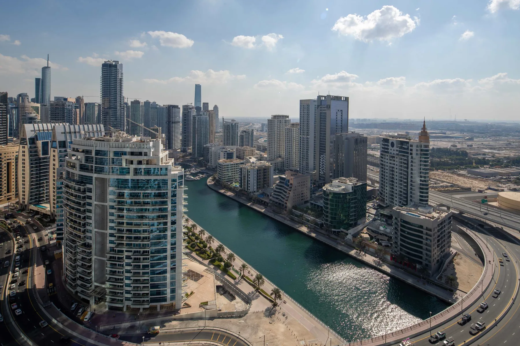 Un canal atraviesa un denso horizonte urbano, entre edificios altos y carreteras.