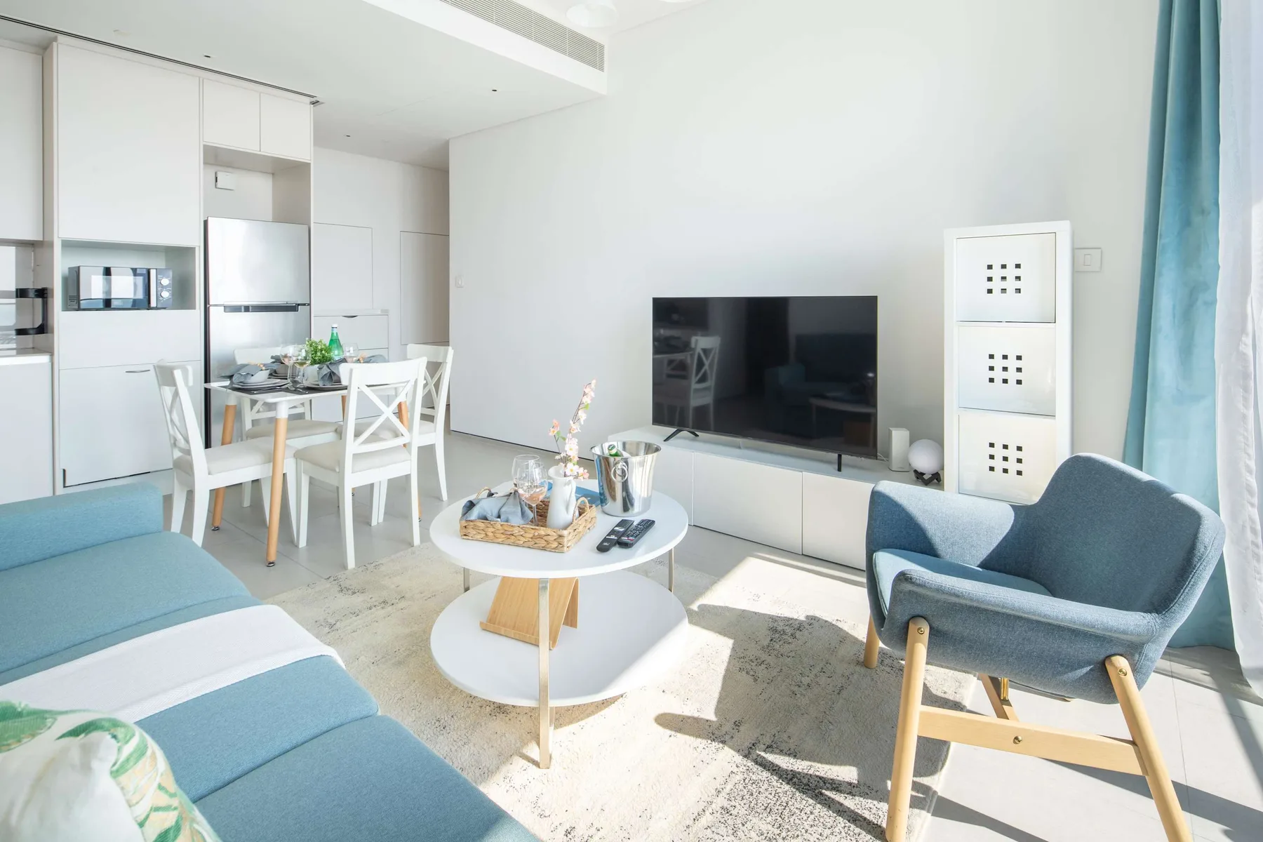 Una luminosa sala de estar y comedor con asientos, una mesa de centro y un televisor.