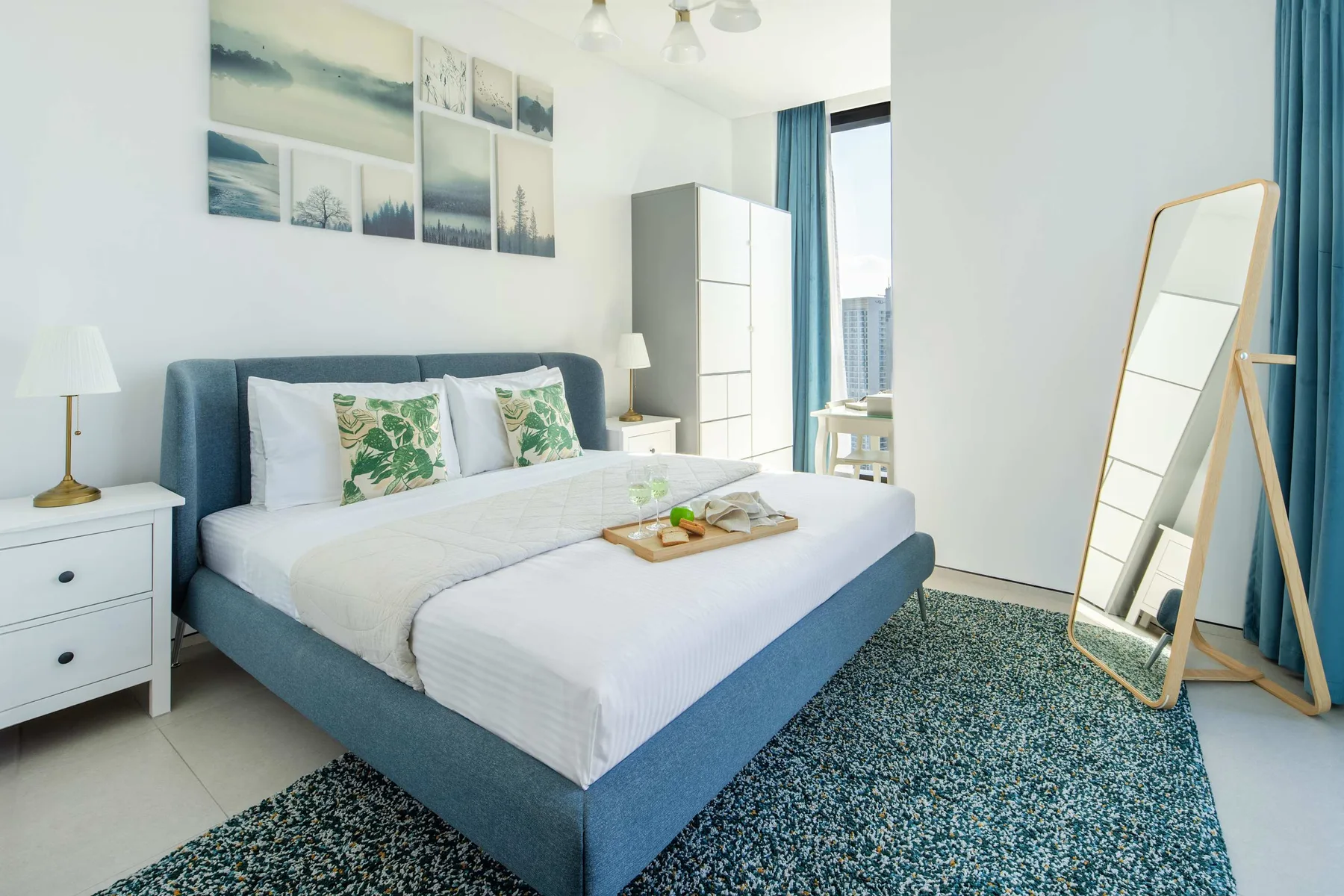 Un dormitorio luminoso con una cama, mesitas de noche y una gran alfombra azul.
