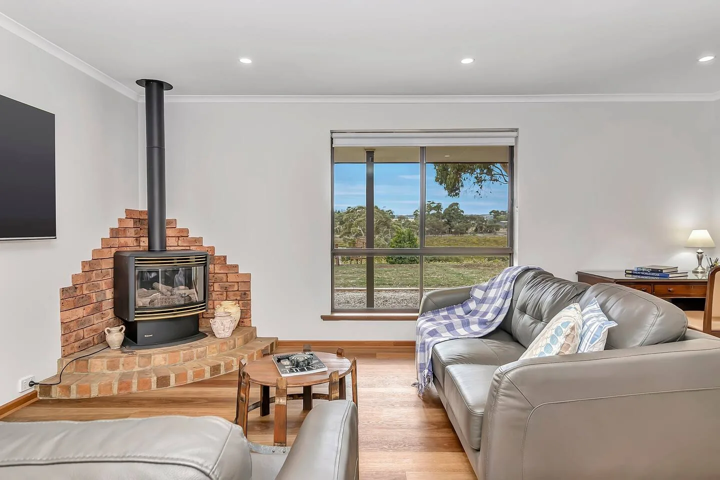 A living room with a brick fireplace, seating, and a large window.