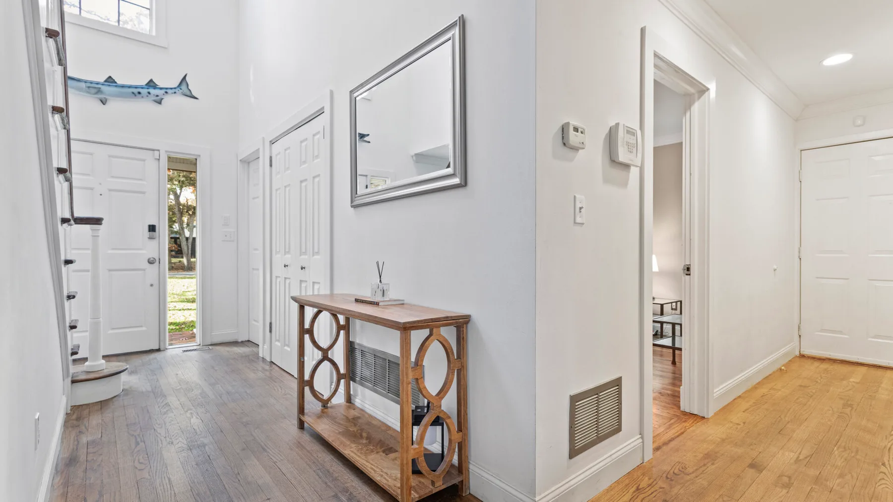 A bright entry hallway has a wooden console table and doors opening to adjoining rooms.