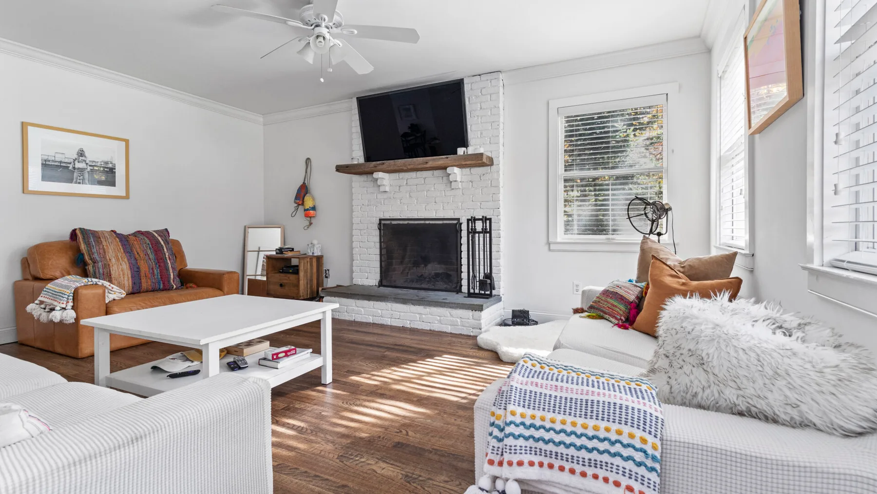 Una sala luminosa con chimenea, asientos y luz del sol sobre el piso.