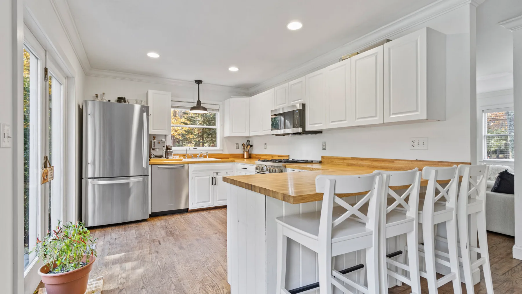 A bright kitchen with white cabinets and a wooden island with seating.