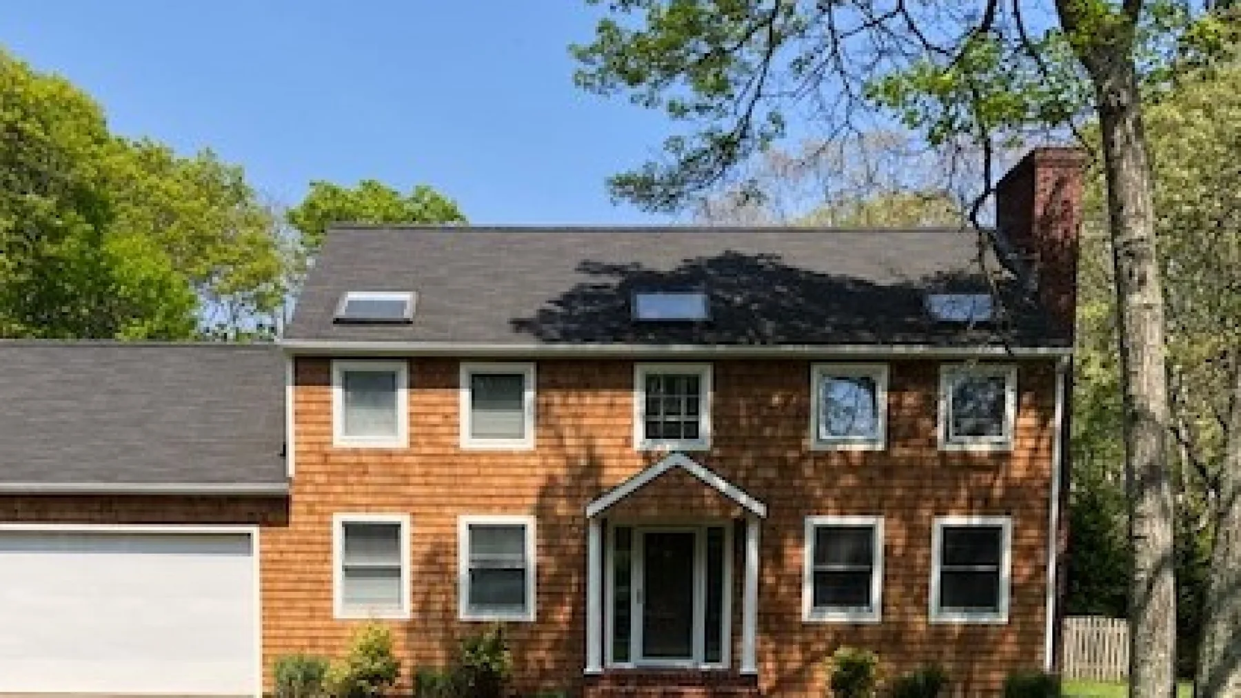 A two-story house with brown siding, white windows, and a garage.