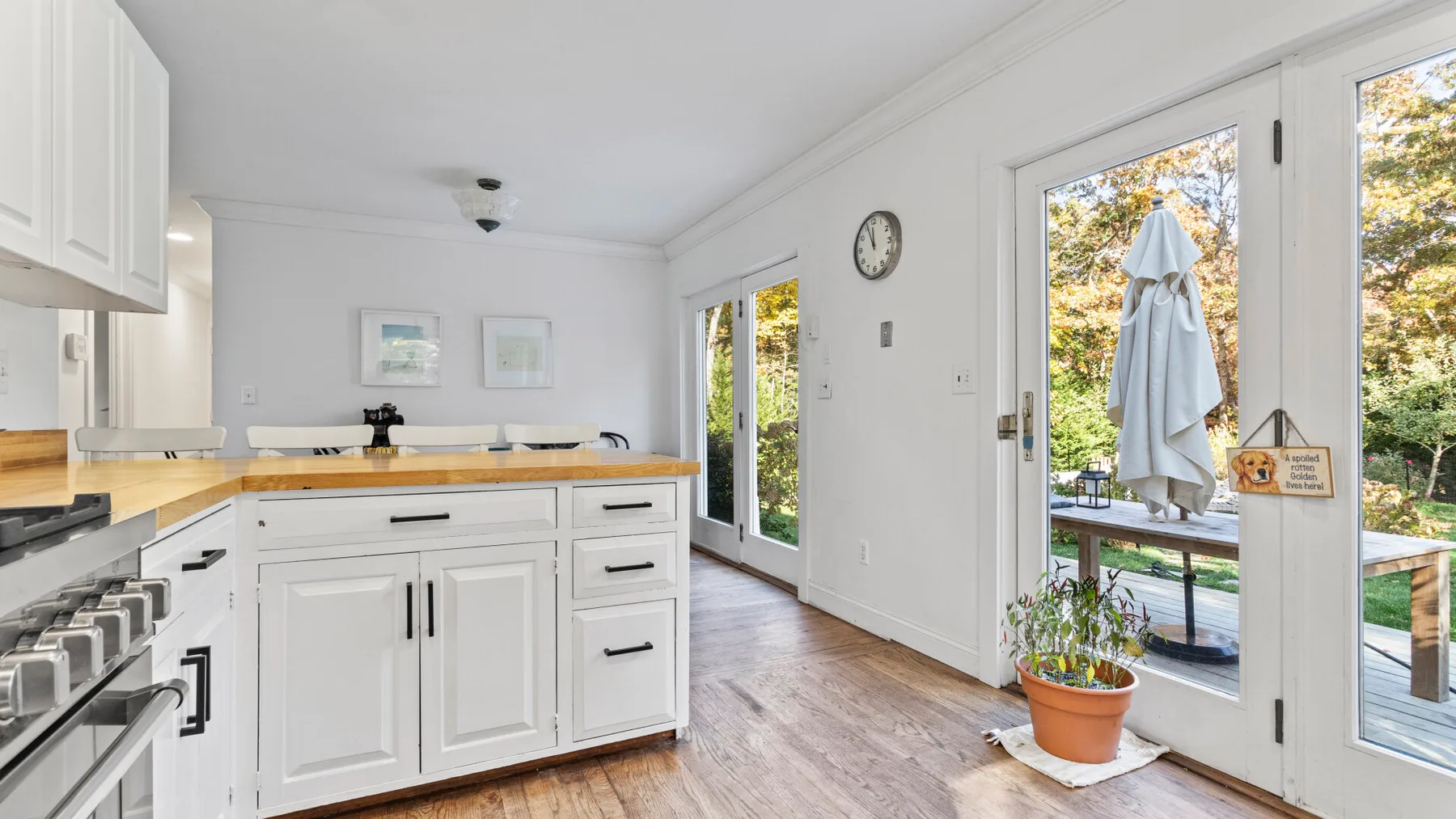 A bright kitchen with white cabinets and a counter beside glass doors.