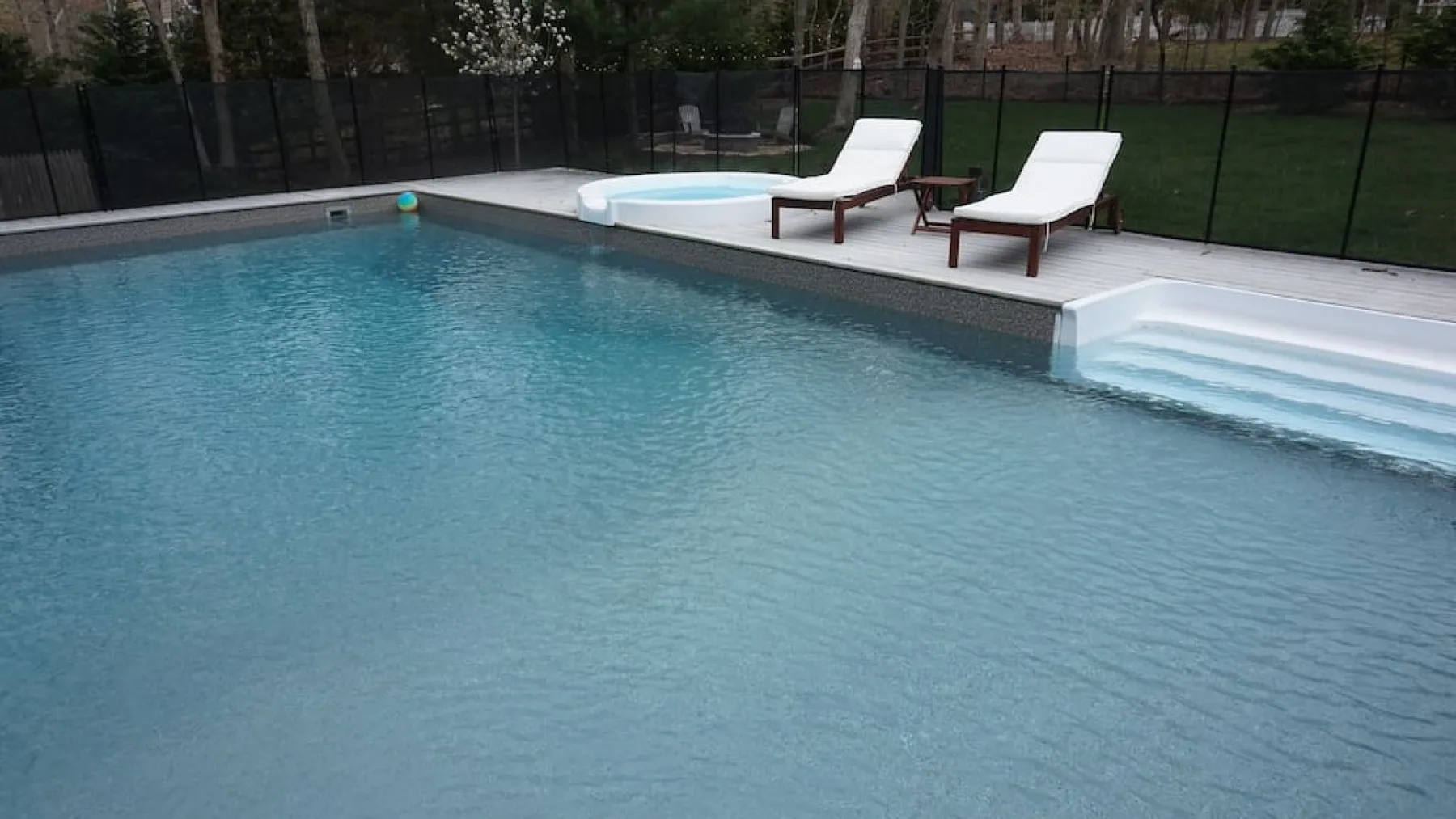 An outdoor swimming pool with lounge chairs beside the water.