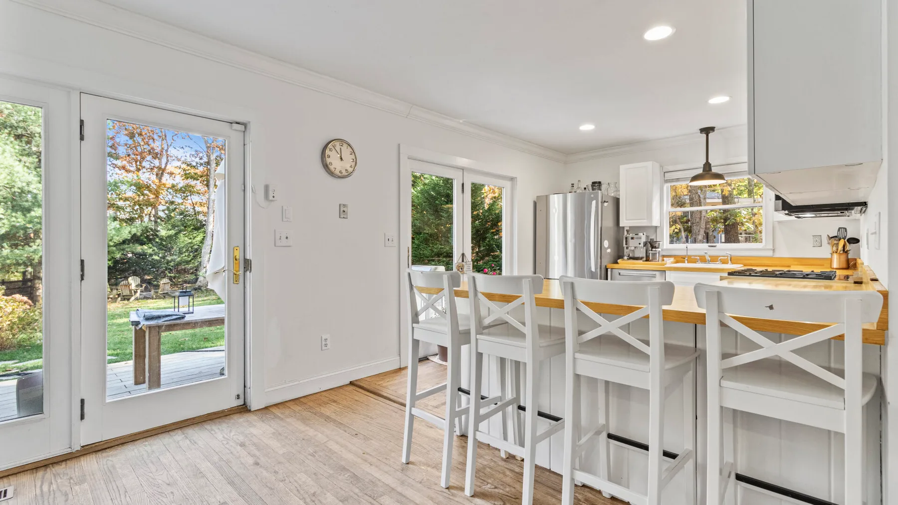 A bright kitchen and dining area features a long counter with white seating.
