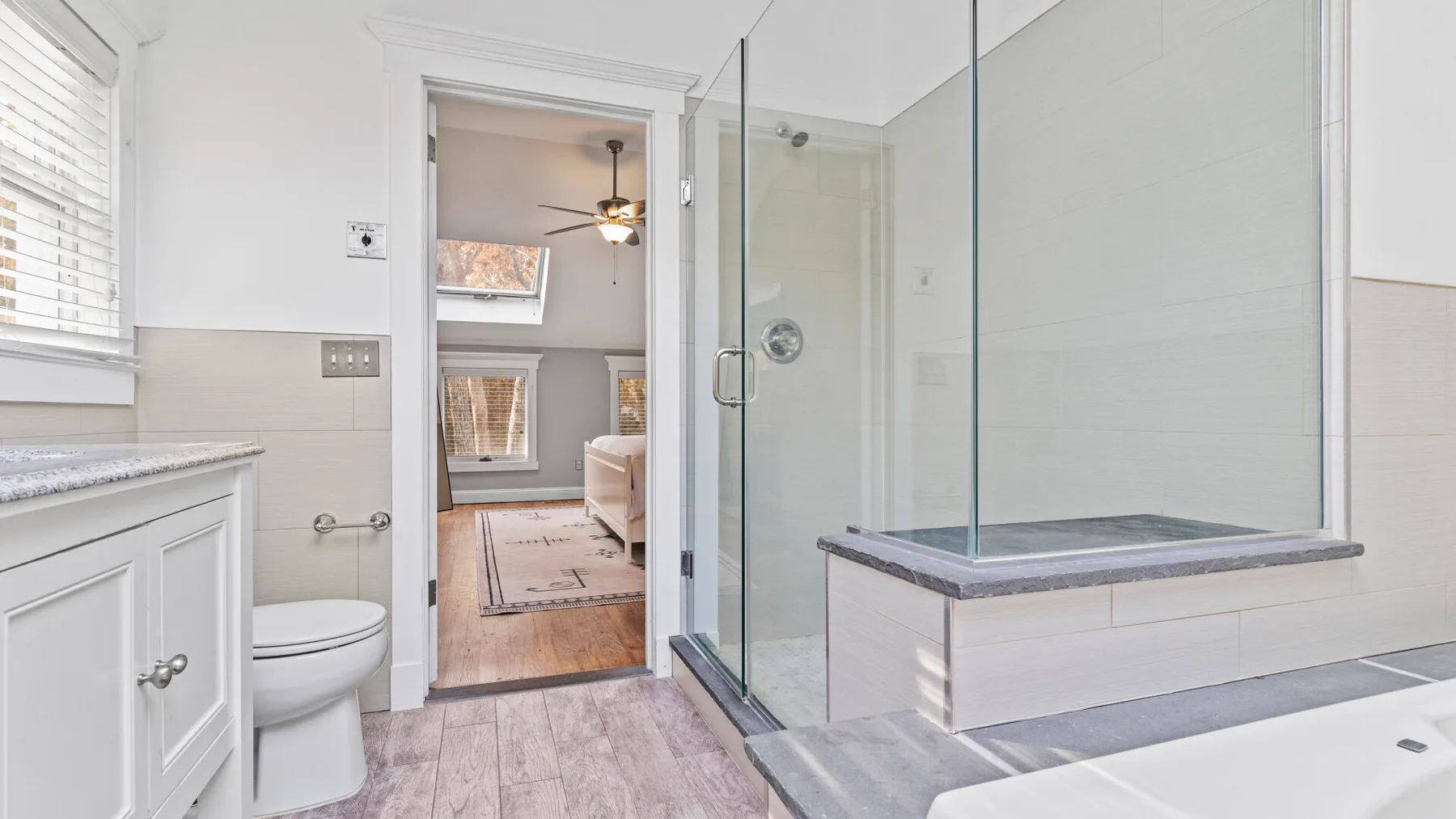 A bright bathroom with a glass shower enclosure and a vanity.