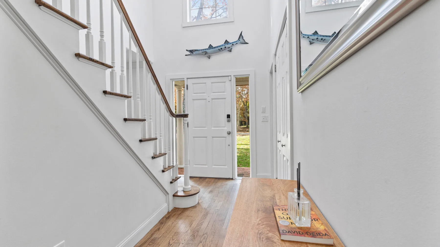 A bright entry hall with a staircase and a white front door.