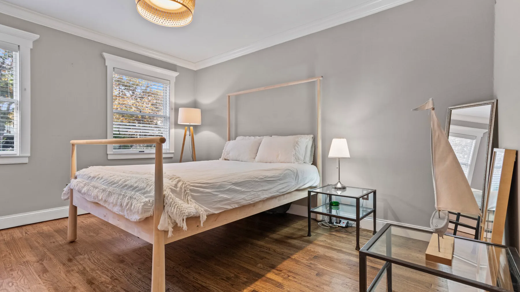 A bedroom with a bed, bedside tables, and windows with blinds.