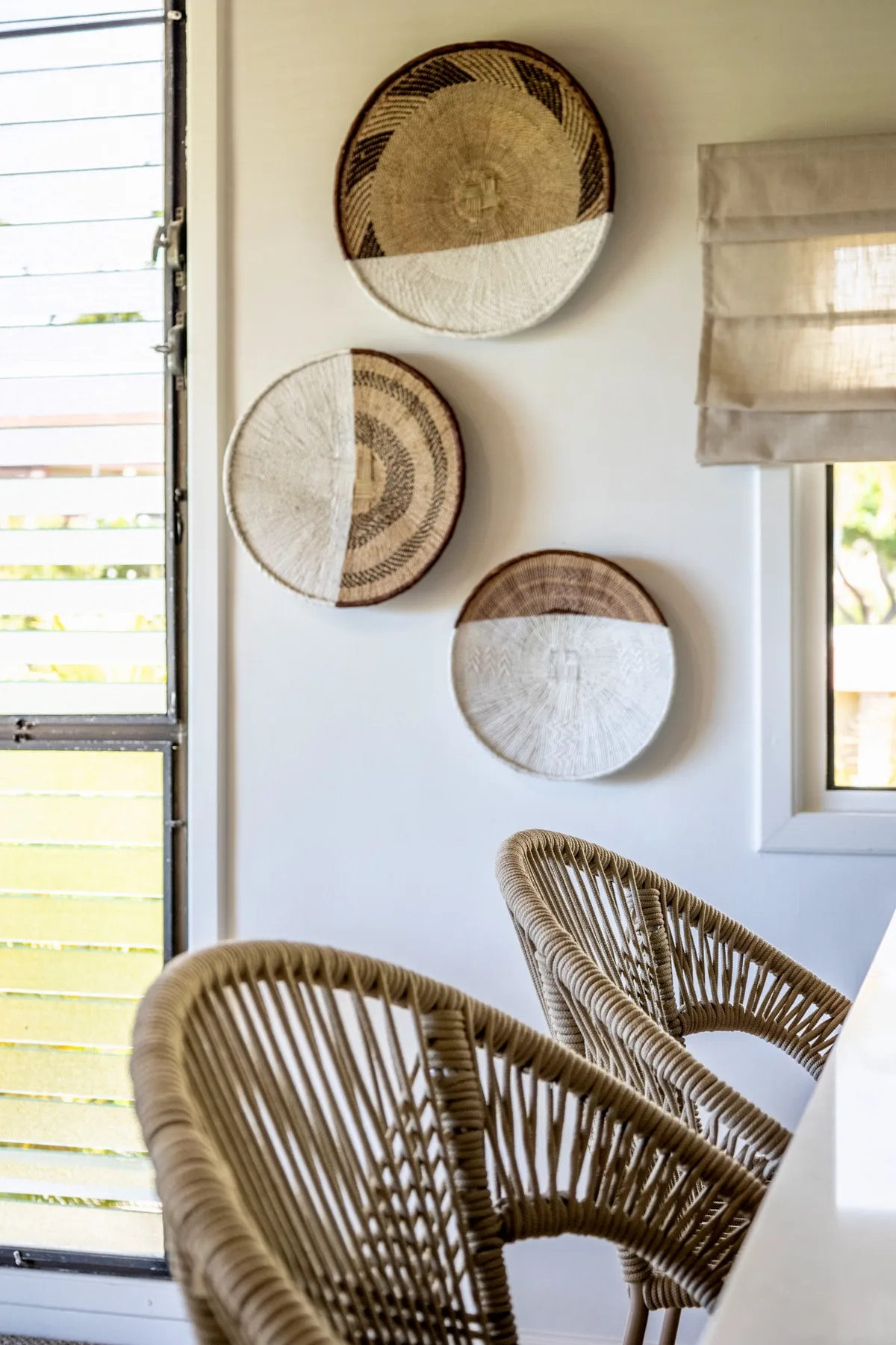 A bright seating area with woven chairs and decorative circular wall hangings.