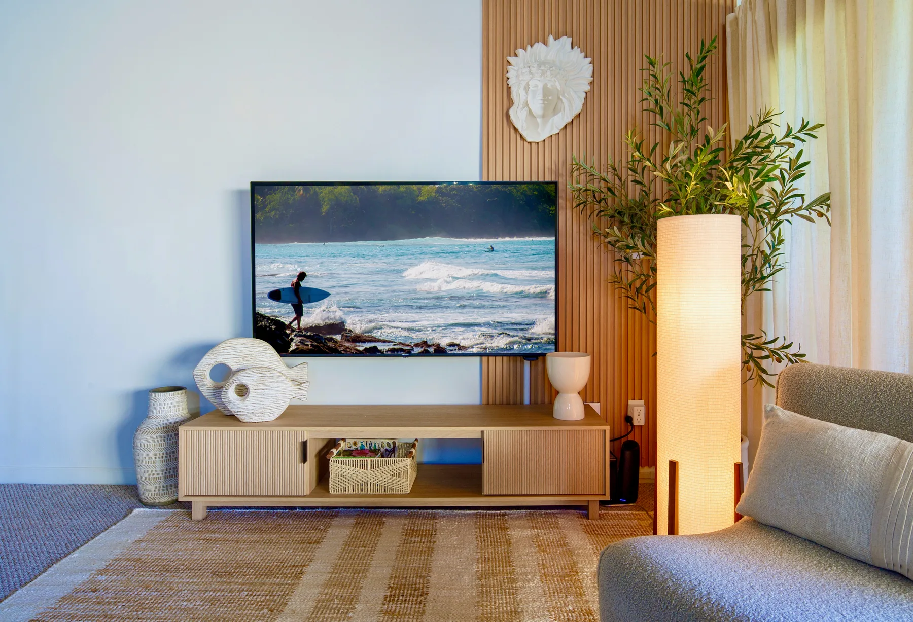 A living room with a television, low cabinet, and floor lamp.