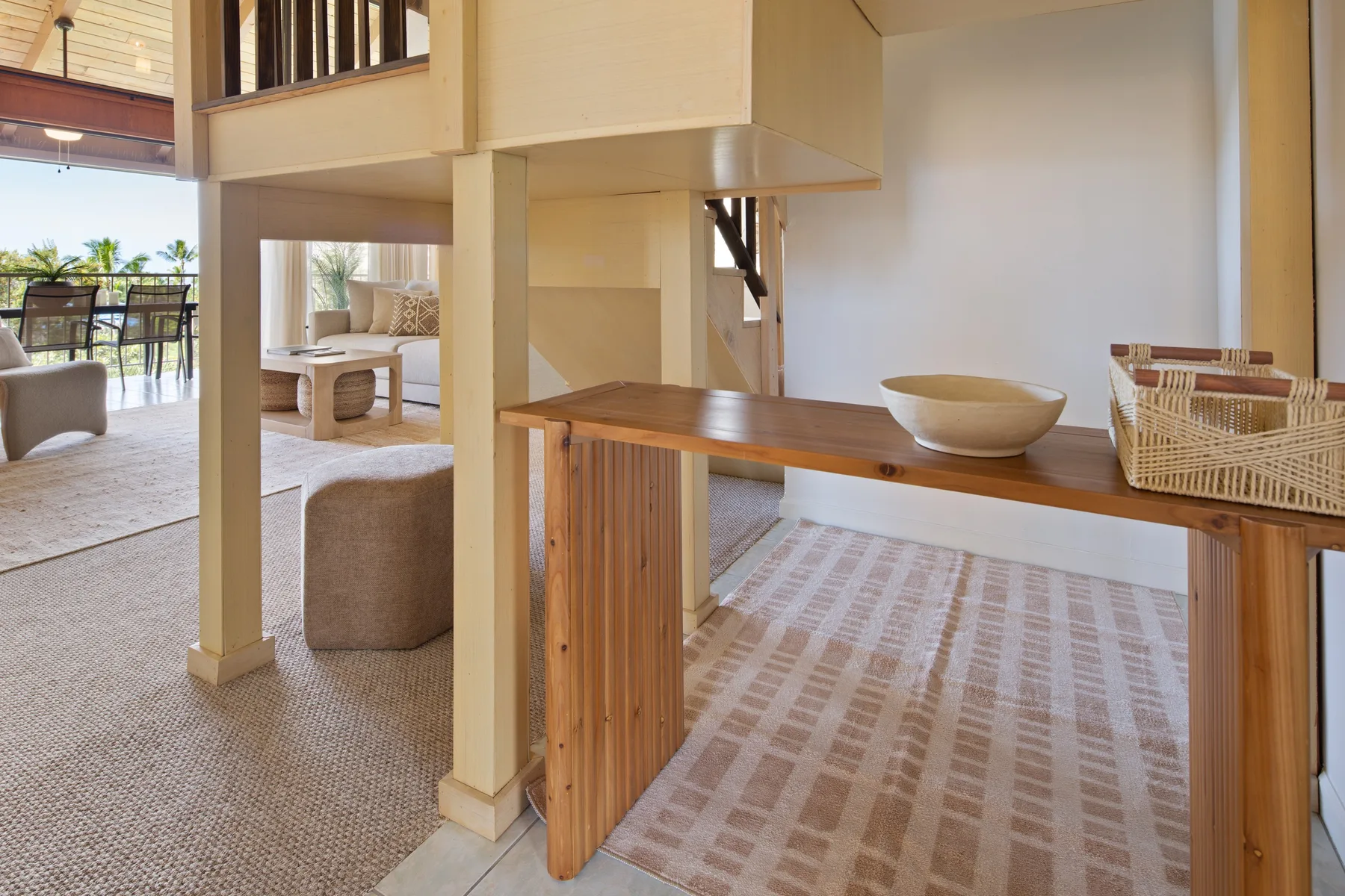 An open-plan living and dining area with a wooden table and woven rugs.