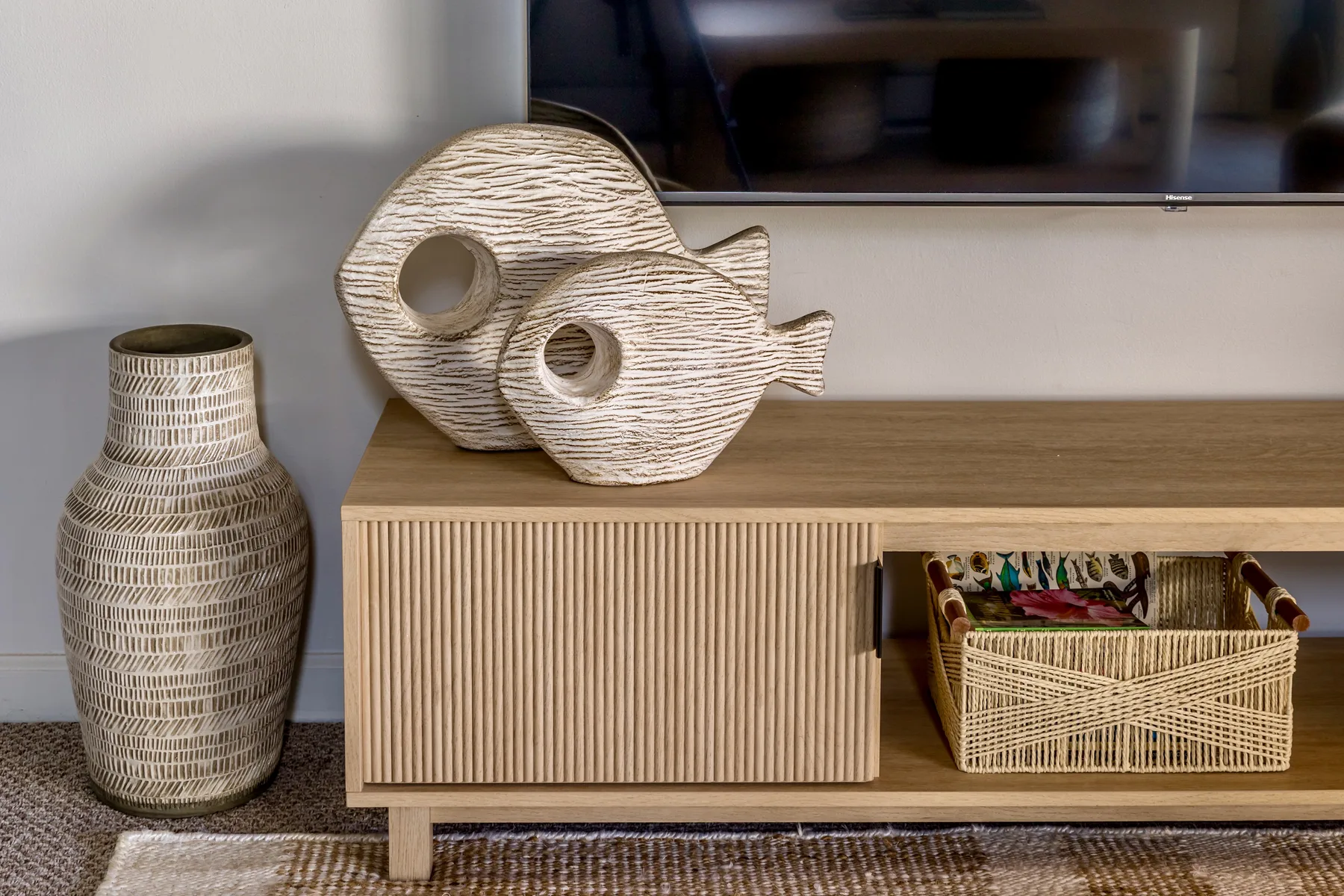A living room media console displays decorative fish sculptures and a woven basket.