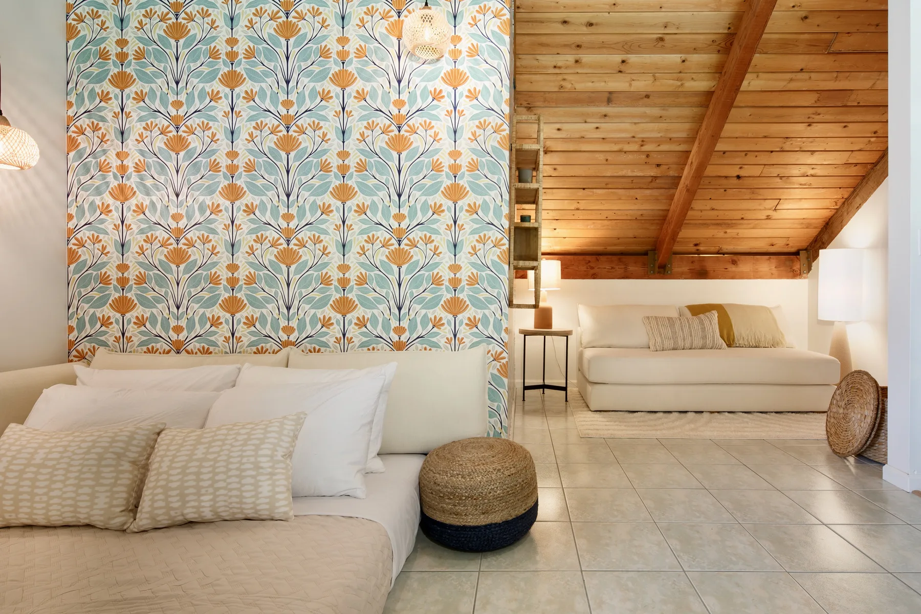 A bedroom with two beds and floral-patterned wallpaper.
