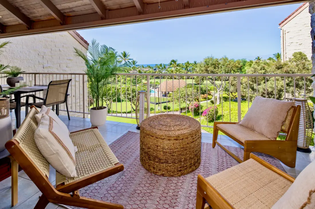 A covered balcony seating area overlooks a garden and the distant sea.