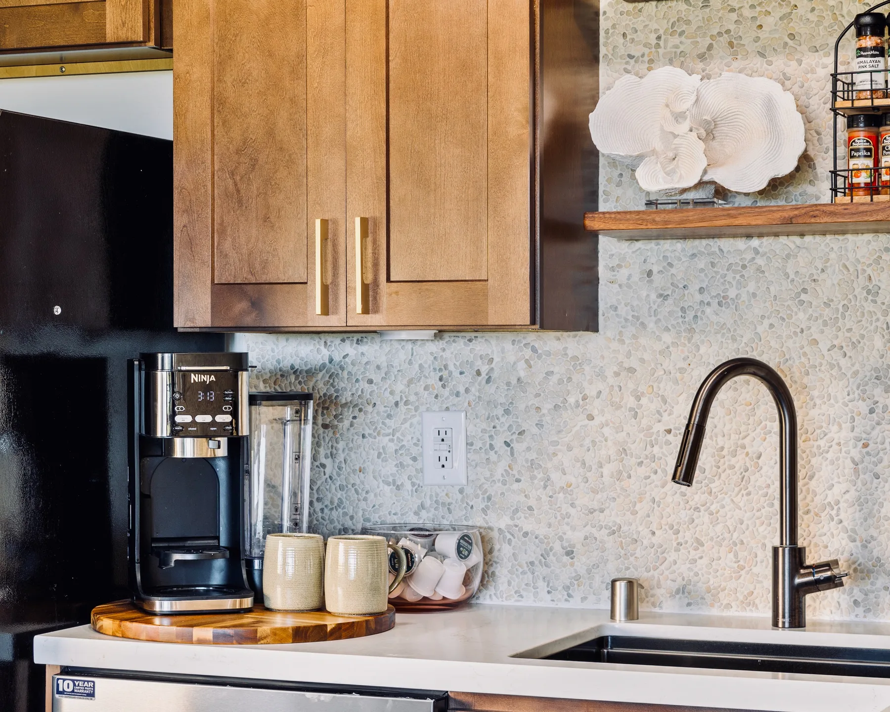 A kitchen counter with a coffee maker, sink, and wooden cabinets.