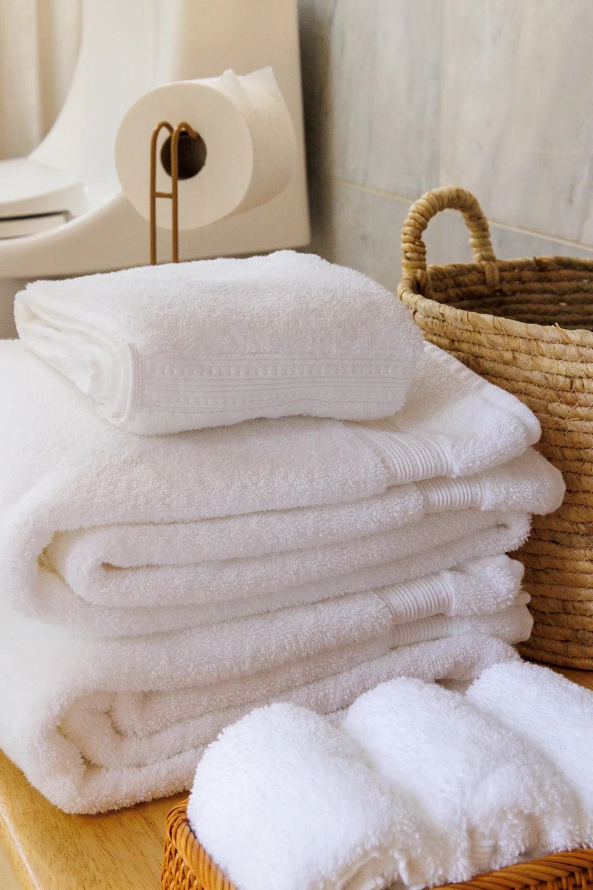 Folded white towels rest beside a woven basket in a bathroom.